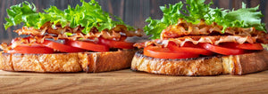 2 BLT Sandwiches sitting on a wood table