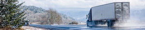 A semi truck driving through the mountains during the winter