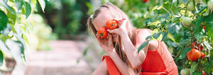 silly child holding tomatoes up to her eyes